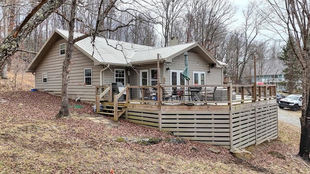 back of property with a chimney, metal roof, and a wooden deck