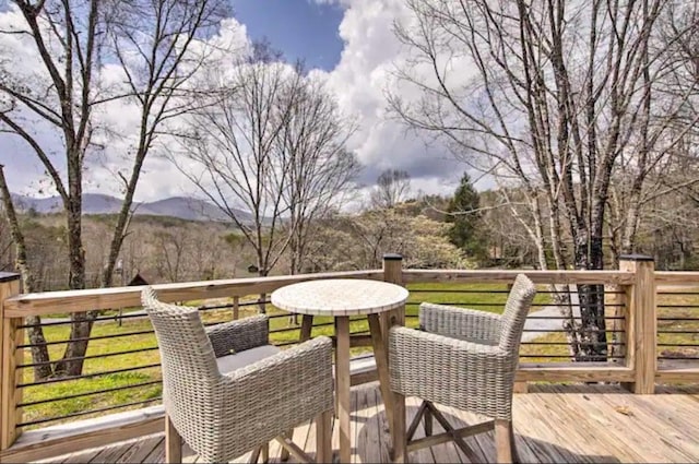 deck featuring a mountain view and a lawn