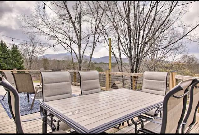 wooden deck with outdoor dining area and a mountain view