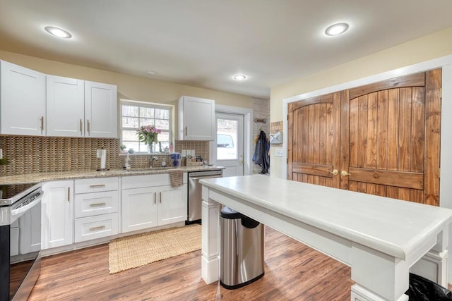 kitchen featuring tasteful backsplash, light wood-style flooring, appliances with stainless steel finishes, white cabinetry, and a sink