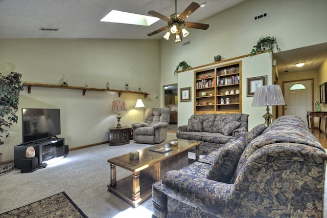 living area featuring a ceiling fan, carpet flooring, high vaulted ceiling, a skylight, and baseboards