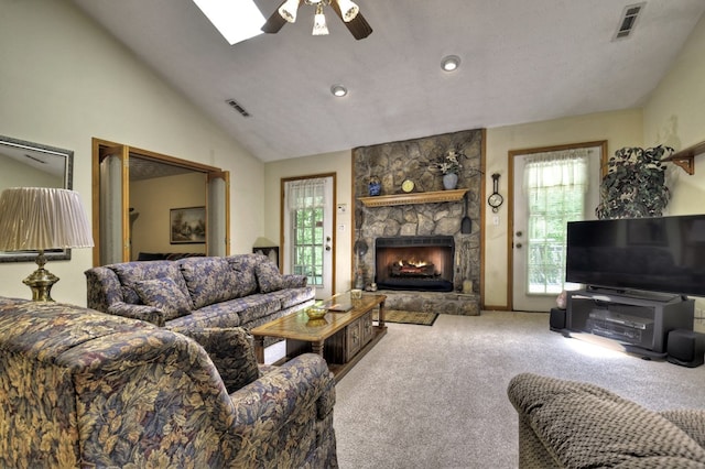 living area with ceiling fan, carpet, a fireplace, lofted ceiling, and a skylight
