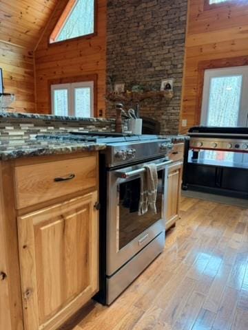 5575 Rainbow Springs Rd, Franklin, NC 28734 - kitchen with stainless steel range with gas stovetop, plenty of natural light, wood walls, light wood-type flooring, and high vaulted ceiling