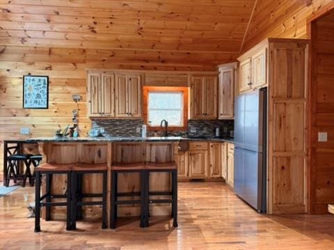 5575 Rainbow Springs Rd, Franklin, NC 28734 - kitchen featuring stainless steel refrigerator, dark countertops, a kitchen bar, light wood-style flooring, and lofted ceiling