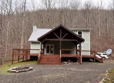 5575 Rainbow Springs Rd, Franklin, NC 28734 - back of house featuring a wooded view, an outdoor fire pit, a wooden deck, a chimney, and metal roof