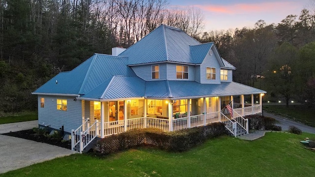 back house at dusk featuring a yard and a porch