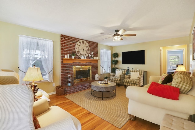 living room with ceiling fan, a fireplace, and hardwood / wood-style floors