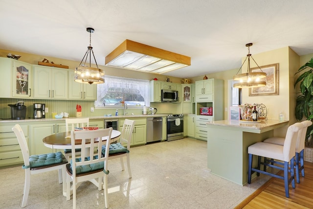 kitchen with appliances with stainless steel finishes, kitchen peninsula, a kitchen breakfast bar, and pendant lighting