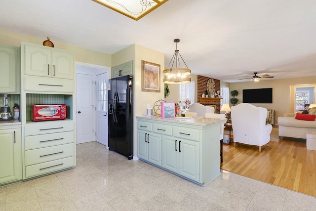 kitchen featuring ceiling fan with notable chandelier, kitchen peninsula, hanging light fixtures, light hardwood / wood-style floors, and black fridge with ice dispenser