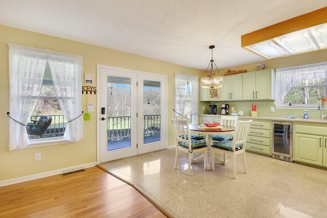 dining space with sink, light wood-type flooring, beverage cooler, a chandelier, and a textured ceiling