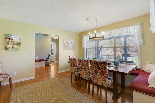 dining room with a chandelier, wood-type flooring, and a textured ceiling