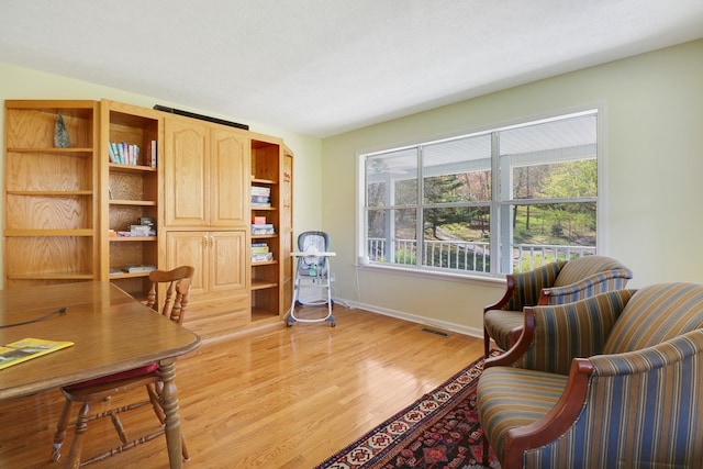 home office with a textured ceiling and light wood-type flooring