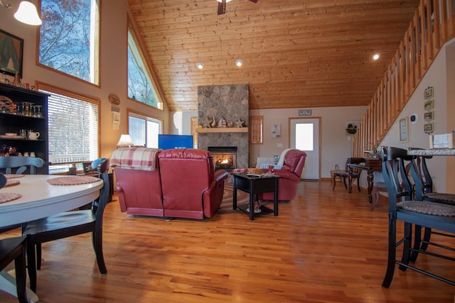 living room with hardwood / wood-style floors, a stone fireplace, wood ceiling, and high vaulted ceiling