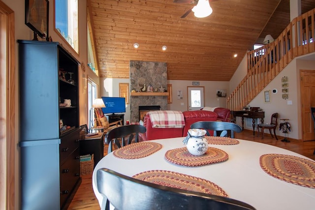 dining space with ceiling fan, high vaulted ceiling, a fireplace, wood ceiling, and hardwood / wood-style flooring