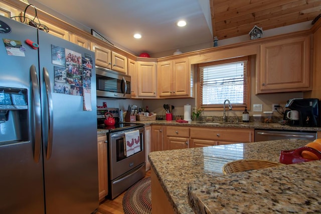 kitchen with light stone counters, sink, light wood-type flooring, and appliances with stainless steel finishes