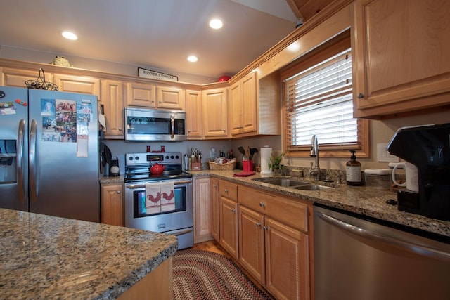 kitchen featuring appliances with stainless steel finishes, light brown cabinets, light stone counters, and sink