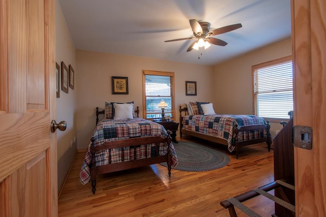 bedroom with ceiling fan, light hardwood / wood-style flooring, and multiple windows