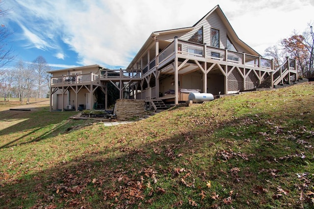 rear view of house featuring a lawn, a sunroom, and a deck