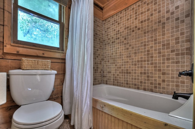 bathroom featuring wooden walls, shower / tub combo, and toilet