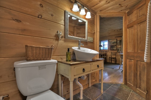 bathroom featuring wooden walls, hardwood / wood-style flooring, sink, and toilet