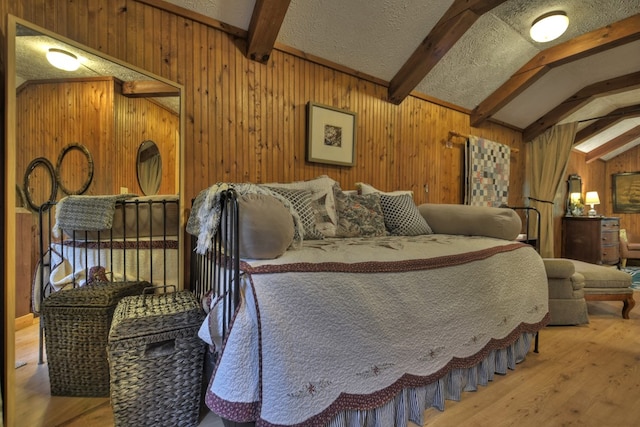 bedroom with a textured ceiling, wood walls, lofted ceiling with beams, and wood-type flooring