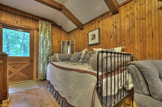 interior space with wooden walls, vaulted ceiling with beams, light hardwood / wood-style floors, and a textured ceiling