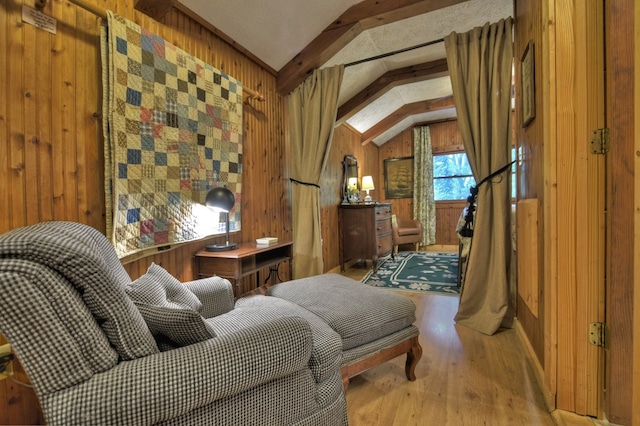 sitting room with light wood-type flooring, wood walls, and lofted ceiling with beams