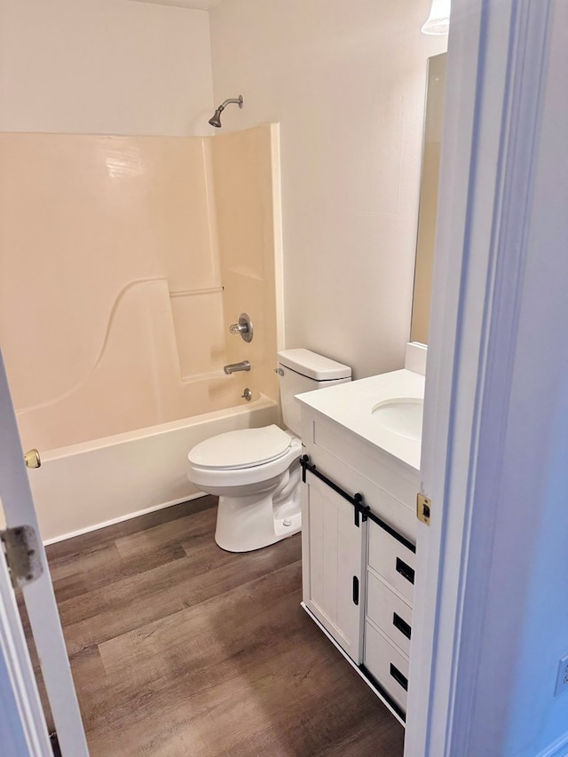 bathroom with vanity, wood finished floors, shower / bathtub combination, and toilet