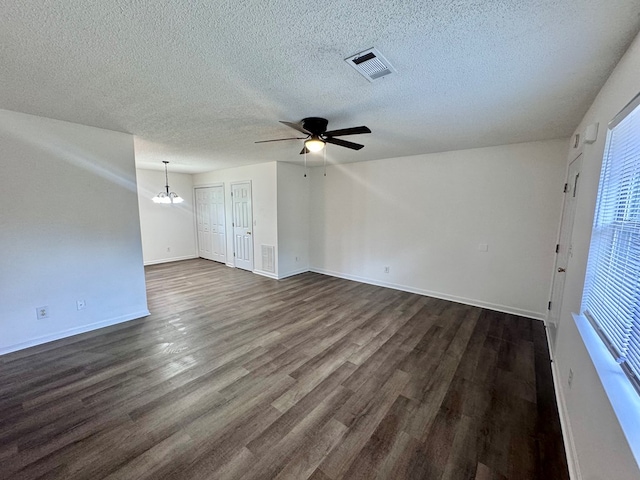 spare room featuring visible vents, dark wood-type flooring, baseboards, ceiling fan with notable chandelier, and a textured ceiling