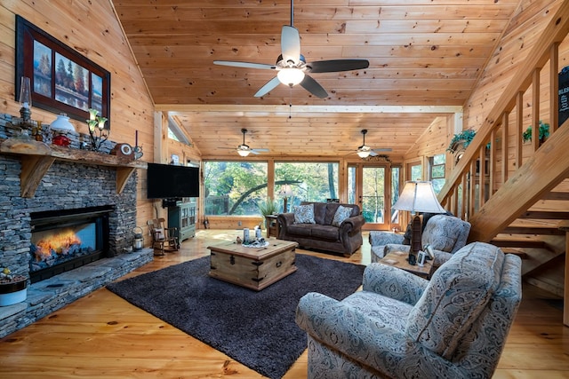 living room with lofted ceiling, wooden ceiling, wooden walls, light wood-type flooring, and a fireplace