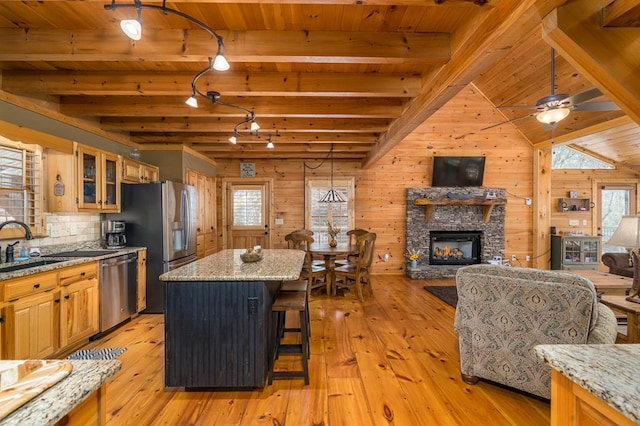 kitchen featuring a center island, stainless steel appliances, light stone counters, and wooden walls