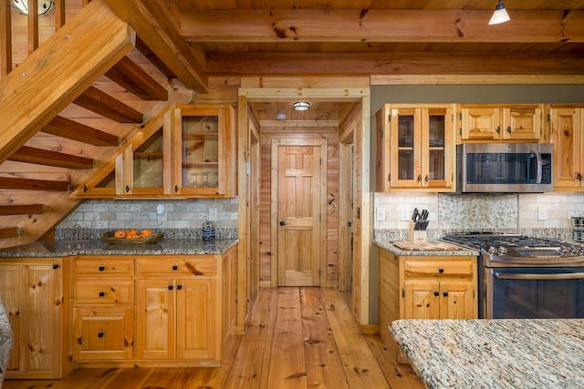 kitchen with light wood-type flooring, light stone countertops, and stainless steel appliances