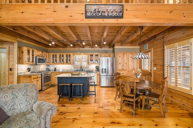 dining space with beam ceiling, wood walls, wooden ceiling, and light wood-type flooring