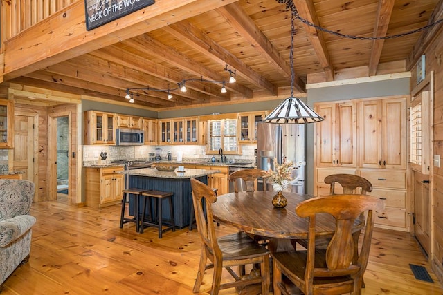 dining area with wood ceiling, wooden walls, sink, beam ceiling, and light hardwood / wood-style floors