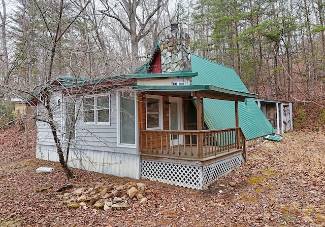 view of front of home featuring covered porch, a chimney, and metal roof