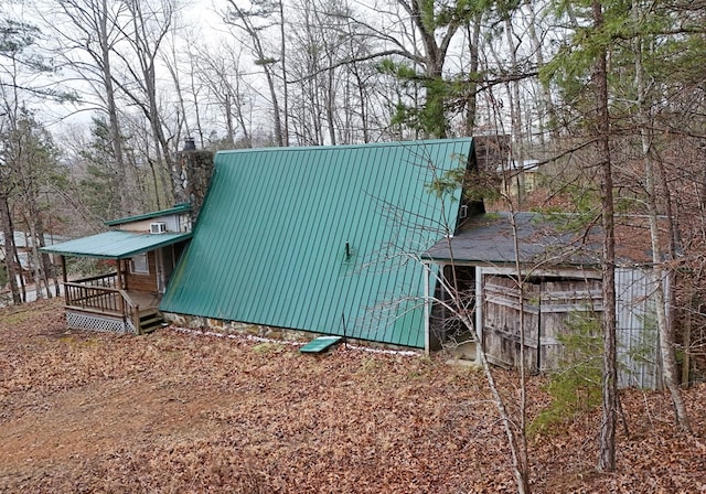 view of side of property with metal roof, a chimney, and a wooden deck