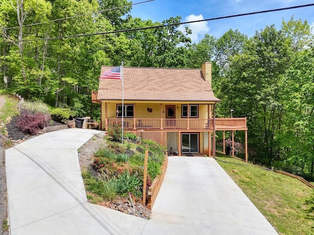 view of front facade with driveway, a chimney, a shingled roof, and a front yard