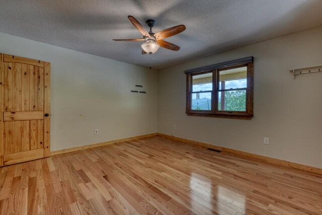empty room featuring light wood-style flooring, ceiling fan, a textured ceiling, and baseboards