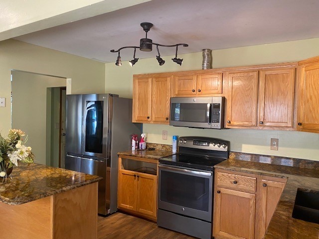 kitchen with dark wood finished floors, stainless steel appliances, a ceiling fan, and dark stone countertops