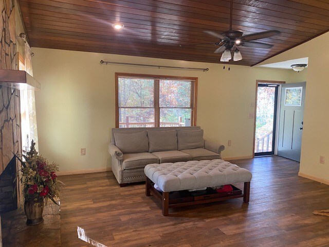 living room featuring wooden ceiling, baseboards, a fireplace, and ceiling fan