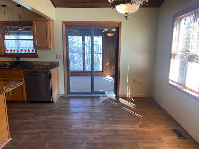 kitchen featuring dishwasher, dark wood-type flooring, baseboards, a sink, and brown cabinets