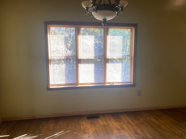 unfurnished dining area with a chandelier, baseboards, and wood finished floors