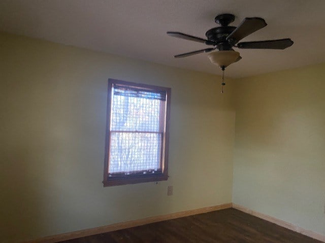 empty room featuring ceiling fan, baseboards, and dark wood finished floors