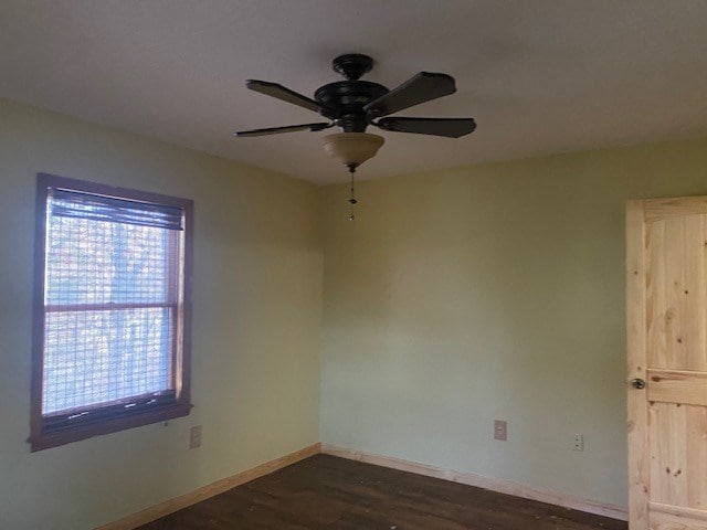 spare room with dark wood-style flooring, baseboards, and a ceiling fan