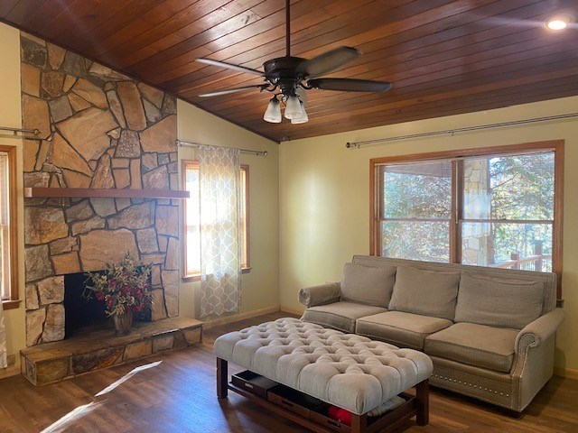living area featuring wooden ceiling, lofted ceiling, wood finished floors, baseboards, and ceiling fan