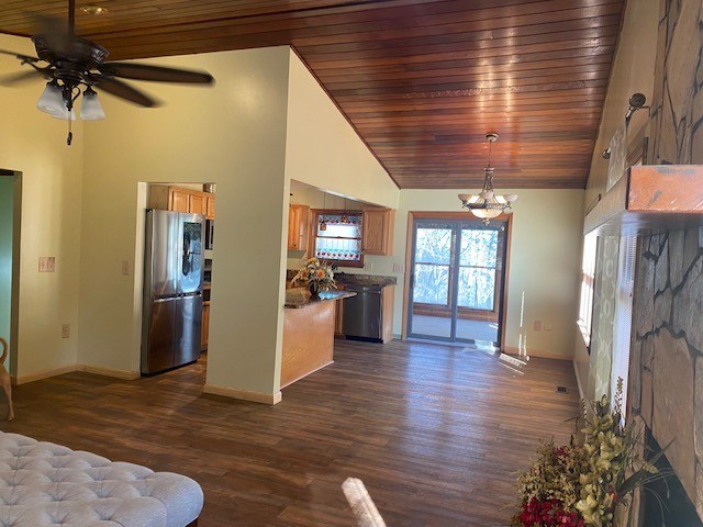 unfurnished living room featuring dark wood-type flooring, baseboards, ceiling fan with notable chandelier, and high vaulted ceiling