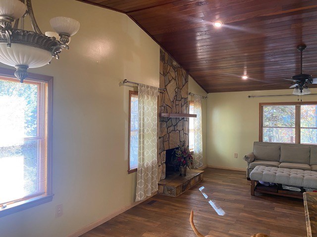 living room with vaulted ceiling, wood ceiling, plenty of natural light, baseboards, and a ceiling fan