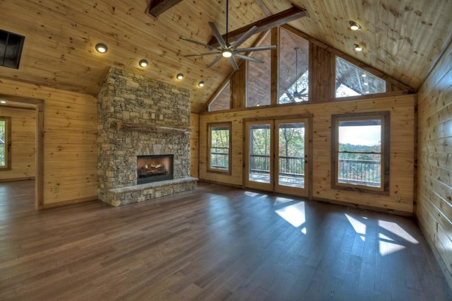 unfurnished living room with wooden ceiling, wooden walls, wood finished floors, and a stone fireplace