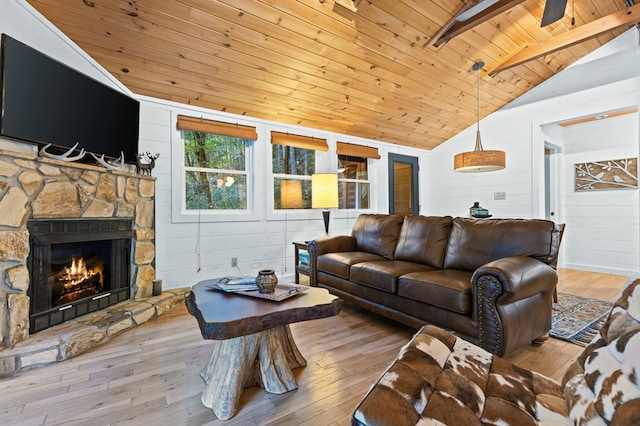 living room with vaulted ceiling with beams, wood walls, wooden ceiling, a fireplace, and light hardwood / wood-style floors