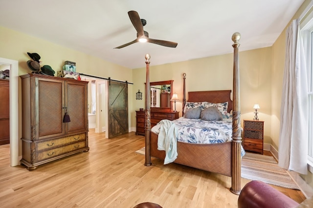 bedroom featuring ceiling fan, light hardwood / wood-style flooring, and a barn door